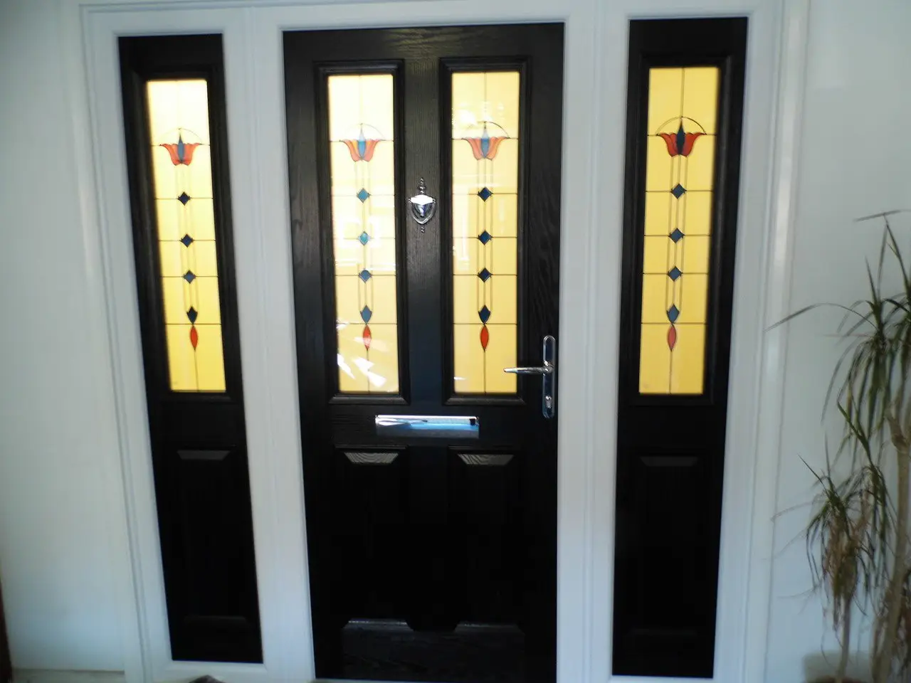 A black composite front door with stained glass panels, between two matching glazed side panels